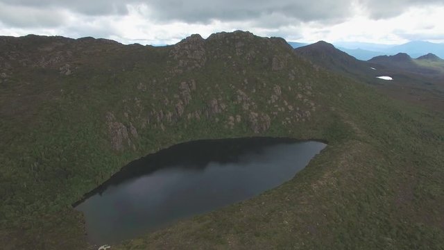 Forward flight over Lake Esperance rising high aboe mountain peaks at Hartz Mountains National Park, Tasmania, Australia