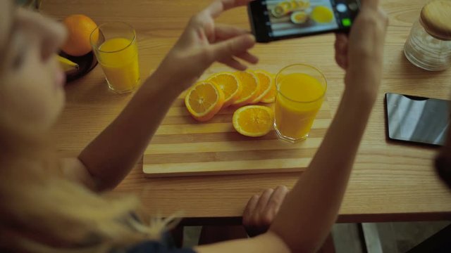Lady taking pictures of tasty oranges.