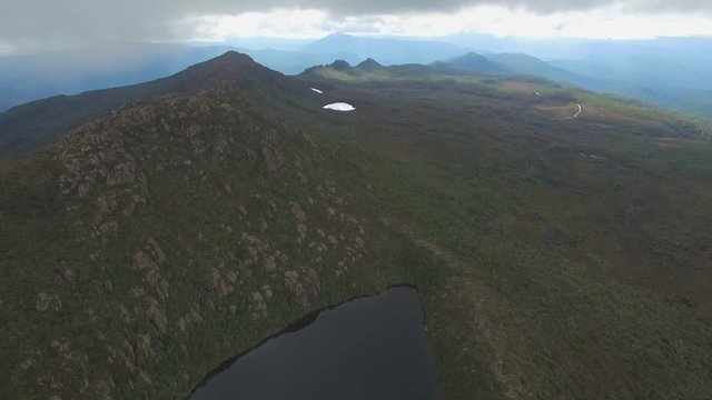 Forward flight above Lake Esperance passing clouds at Hartz Mountains National Park, Tasmania, Australia
