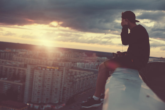 Brave man sitting above the city and listening music