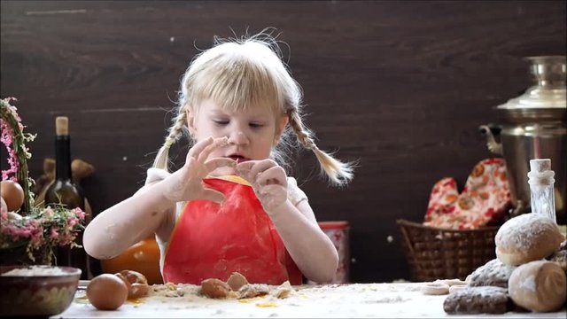 Little girl funny playing with flour. Kitchen table for cooking, ingredients for baking 