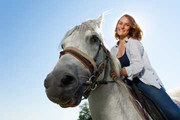 Obraz premium Portrait of happy young woman riding white horse
