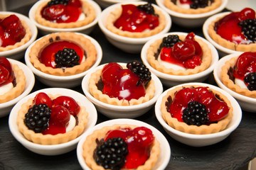  mini cherry pies/tarts on  plates garnished with blackberry