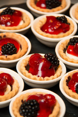 mini cherry pies/tarts on  plates garnished with blackberry