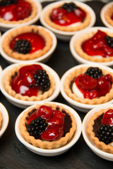  mini cherry pies/tarts on  plates garnished with blackberry