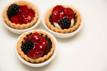  mini cherry pies/tarts on  plates garnished with blackberry