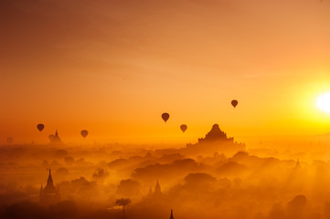 Amazing misty sunrise colors and balloons silhouettes over ancient Dhammayan Gyi Pagoda. Architecture of old Buddhist Temples at Bagan Kingdom. Myanmar (Burma). Travel landscapes and destinations