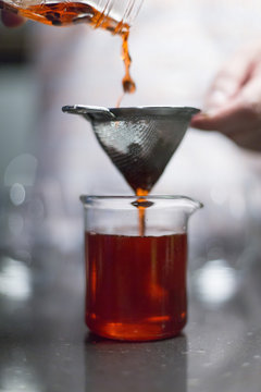 Person mixing drinks through a seive