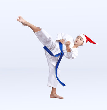 Roundhouse kick karate boy beats in a cap of Santa Claus