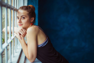 Picture of a pretty lady standing before white window bars