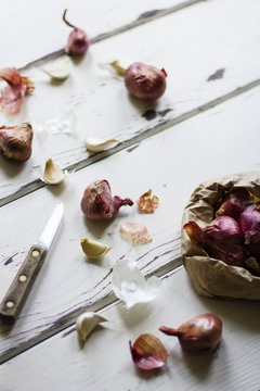 Shallots and garlic, with knife on white wood
