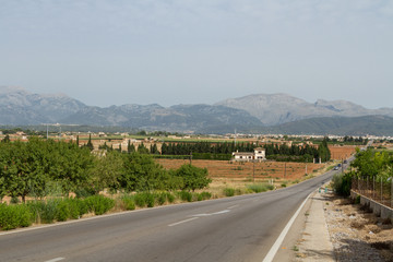 Landsväg genom odlingslandskap med berg i bakgrunden