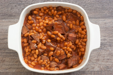 easy leftover roast beef chunks and beans in tomato sauce baked in casserole dish closeup