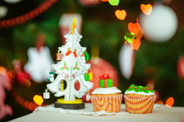 Toy Christmas tree and tasty little cupcakes stand on the table