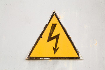 Old iron electrical locker doors. On the door is a warning sign of lightning bolt. Focus point on the lightning.