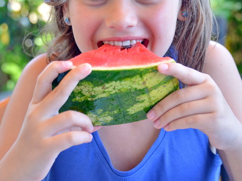 una bambina mangia con gusto una fetta di anguria