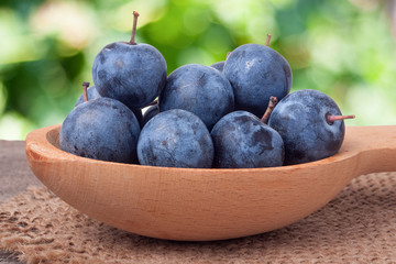 blackthorn berries in a wooden spoon on table with sacking and blurred background