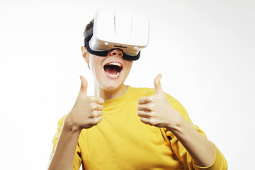 Teenager with virtual reality headset is stunned by VR experience. Teen wearing in vr glasses holding finger up on a white background. New technologies and young person.