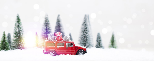 Snowy Winter Forest with miniature red car carrying christmas presents
