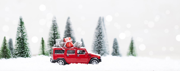 Snowy Winter Forest with miniature red car carrying christmas presents