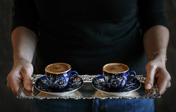 Woman serving Turkish coffee on silver tray