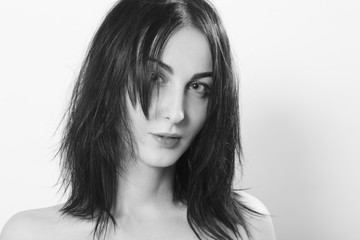 beautiful woman with fluffy hair looking at camera on white background, monochrome