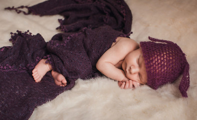 Pretty kid in violet hat with ears sleeps on fluffy blanket