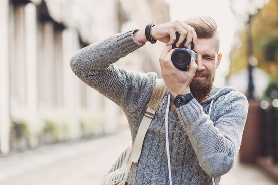 Young cheerful man photographer takes images with camera