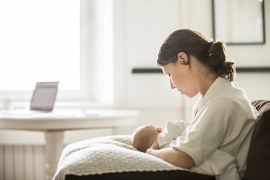 Profile portrait of a young attractive woman breastfeeding a child, holding on her knees, family concept photo