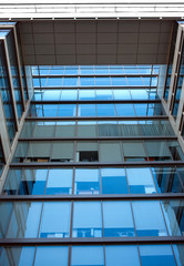 Facade with glass wall of modern office building with many large panoramic windows with gray curtains in business cluster top section front view close-up