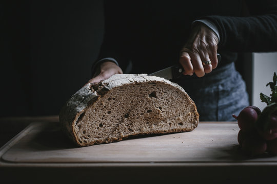 Woman slicing big loaf of whole wheat bread