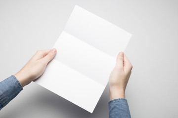 Hands are holding a Dl Tri-Fold white paper Flyer