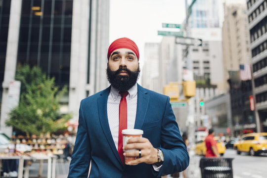 Businessman walking with coffee in street, Manhattan, New York, USA