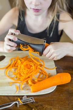 Girl using spiral vegetable slicer, partial view