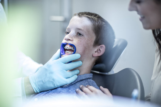Boy with mother in dental surgery receiving orthodontic treatment