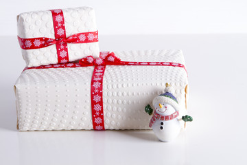 Two white gift boxes with polka dots with red ribbon and tree toy snowman