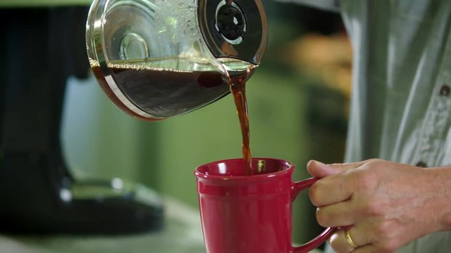 Man pouring coffee into red cup