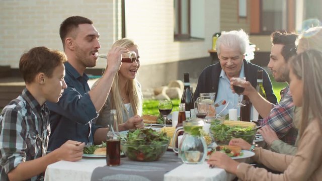 Group of Mixed Race People Having fun, Communicating and Eating at Outdoor Family Dinner