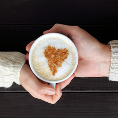 coffee break for two/ frothy cappuccino with heart symbol in hands top view