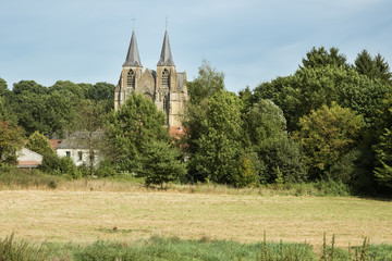 Fototapeta na wymiar The field Basilica. Our Lady of Avioth seen from the fields, surrounded by a pastoral landscape