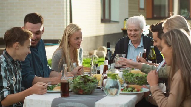 Group of Mixed Race People Having fun, Communicating and Eating at Outdoor Family Dinner