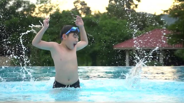 Slow motion of Young Asian boy having fun at pool, happy asian child playing in pool.
