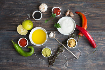  Sauces, spice, herbs, oil, condiments, seeds,cream, vegetables, lime, peppers, dried herbs, bowls, spoon on rustic wooden table. Selective focus.