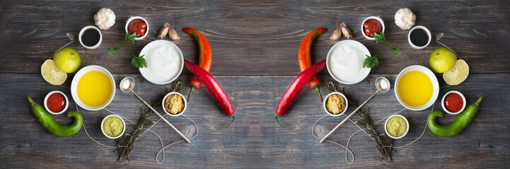 Sauces, spice, herbs, oil, condiments, seeds,cream, vegetables, lime, peppers, dried herbs, bowls, spoon on rustic wooden table. Selective focus. Wide panoramic.