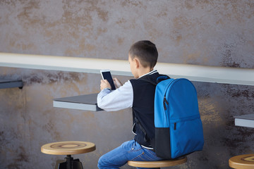 schoolboy using smartphone in cafe