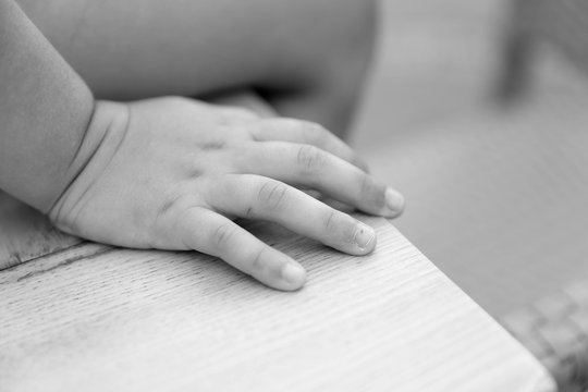 closeup of a child's hand sitting on a desk,