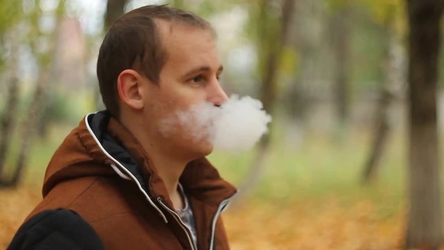 Man smoking electronic sigarette in the forest