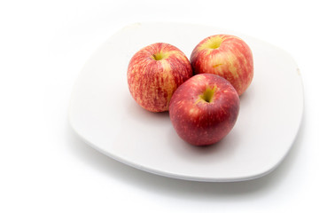 Three fresh red apples with drops isolated on dish white background.