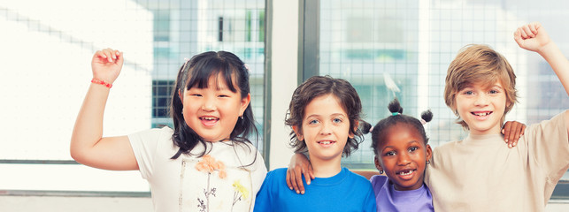 Happy multi ethnic classmates hugging at primary school