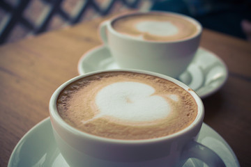 Top view two coffee cup latte art on wood table vintage tone.